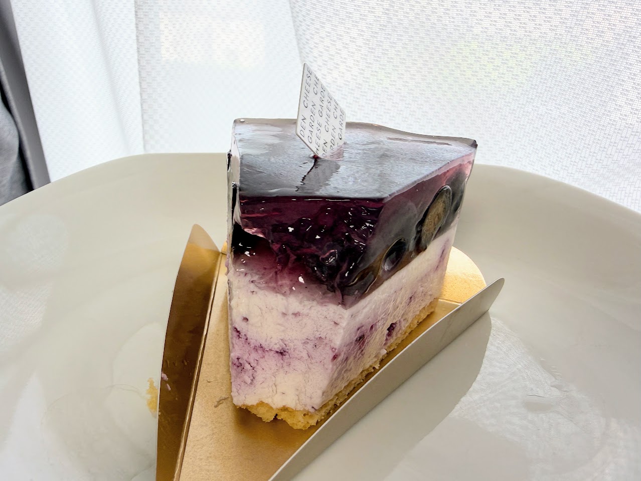 一口食べたブルーベリーレアチーズケーキの断面。ゼリーとレアチーズの層が見える