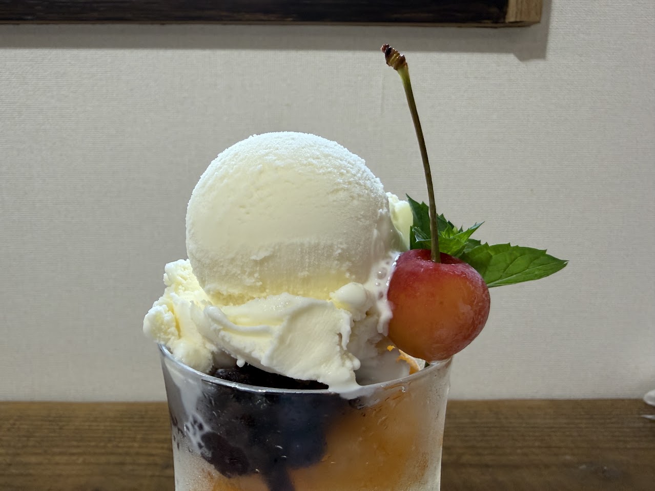 アイスフルーツあんみつの上に載ったバニラアイスとさくらんぼの寄り